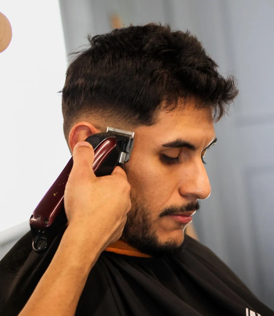 Close-up of a barber using clippers during an adult client's haircut at Chingon Cuh’ts