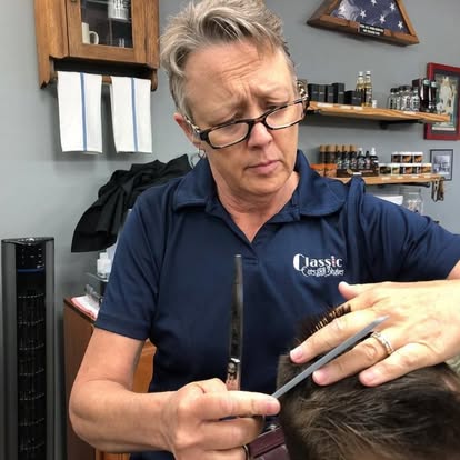 A barber at Classic Cuts and Shaves carefully trimming a client's hair